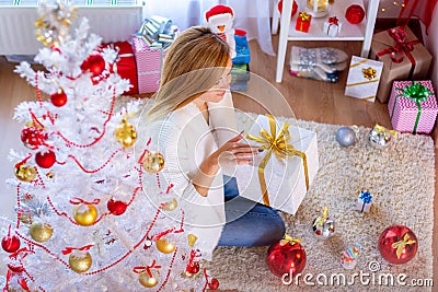 Girl opens New Year`s gift at the Christmas tree Stock Photo