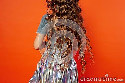 Girl on orange background in the Studio. Very long curly hair like in a fairy tale.Rapunzel. developing in the movement Stock Photo