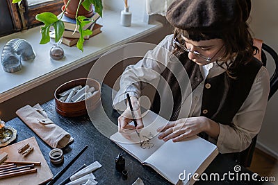 Girl paintress illustrator animator freelancer creates new characters in sketchbook sitting at desk. Stock Photo