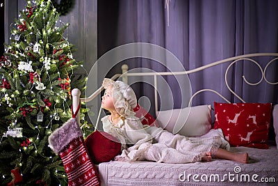 A girl in pajamas lies on a bed next to a Christmas tree Stock Photo