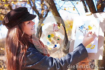 Girl with palette in hand sketches on paper Stock Photo