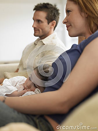 Girl And Parents Watching TV At Home Stock Photo