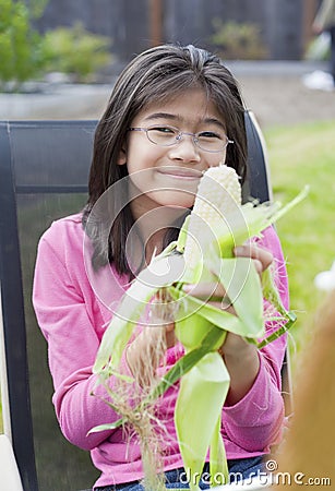 Girl peeling husk off corn cob Stock Photo