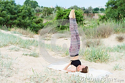Girl performs inverted yoga asanas outdoors, candle pose Stock Photo