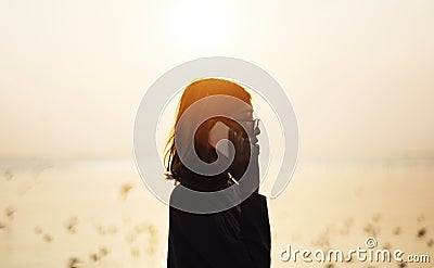 Girl on the phone by the sea sihouette Stock Photo