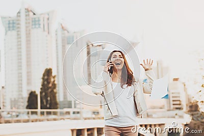 Girl on phone throwing papers in air outdoors. Stock Photo