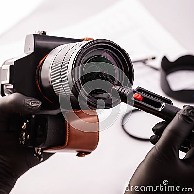 A girl photographer in gloves cleans the lens with special tools for cleaning professional optics. Stock Photo