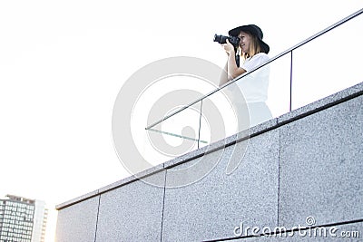 Girl photographer, photographs the city on the roof of the house, a woman tourist looks from the balcony of the hotel at sunset Stock Photo