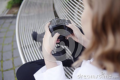 Girl photographer is trying to figure out the settings of the camera, model looks at screen of a SLR camera and learns settings, Stock Photo