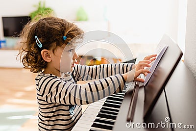 Girl piano student places a sheet of music on her piano to practice Stock Photo