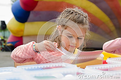 Girl with pigtails draws a picture with colored sand. child creative development concept Editorial Stock Photo