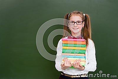 Girl with a pile books near empty green chalkboard Stock Photo