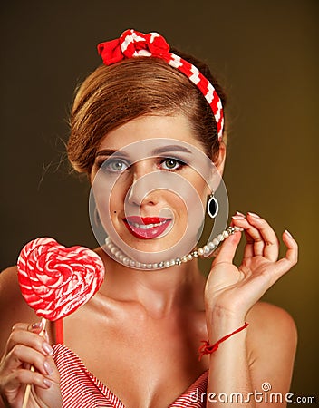 Girl in pin-up style lick striped lollipops. Stock Photo