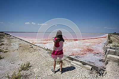 Girl in pink dress against red salt lake in Saline Margherita di Savoia of Italy Stock Photo