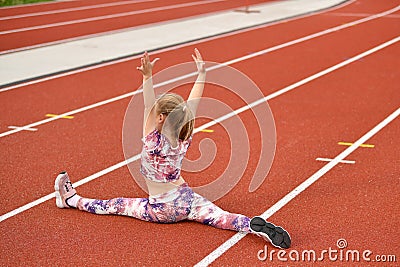 A girl in a legging doing splits at the stadium Stock Photo