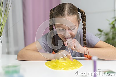 Girl play with yellow slime inflates bubble fun at home Stock Photo