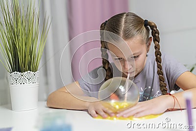 Girl play with yellow slime inflates bubble fun at home Stock Photo