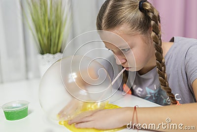 Girl play with yellow slime inflates bubble fun at home Stock Photo