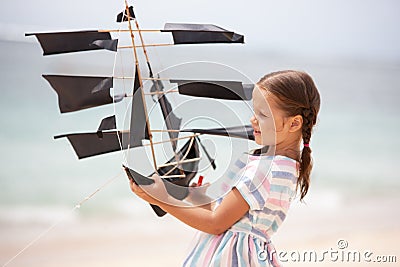 Girl playing on beach flying ship kite. Child enjoying summer. Stock Photo