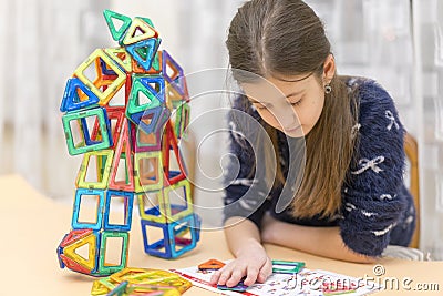 Girl playing colorful magnet plastic blocks kit at indoor playground. girl made a toy robot. The child playing educational games. Stock Photo