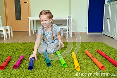 Girl playing with colourful musical tubes. Stock Photo