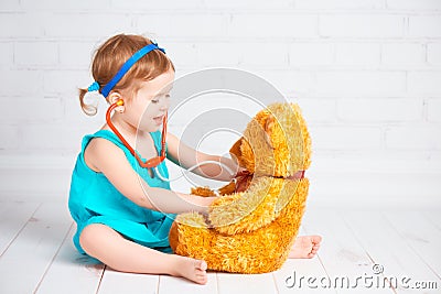 Girl playing doctor and treats teddy bear Stock Photo