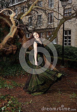 Girl playing with her Victorian dress in the park Stock Photo