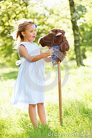 Girl Playing With Hobby Horse In Summer Field Stock Photo