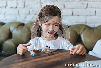 Girl playing with small figures sitting on soft Stock Photo