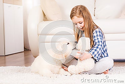 Girl playing with teddy bear and retriever puppy Stock Photo