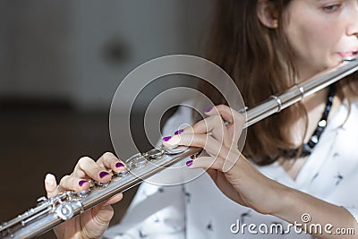 Girl plays on flute. Flute in hands of girl during the concert. Professional musician playing on flute Stock Photo