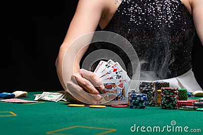 Girl plays poker in a casino, with chips, dollars, and wine. Concept of the gaming business. With space on a black background Stock Photo