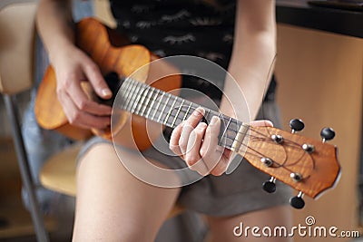 The girl plays on the ukulele. Lesson playing the guitar. Stock Photo