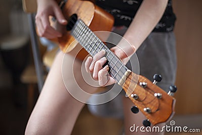 The girl plays on the ukulele. Lesson playing the guitar. Stock Photo