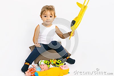 The girl plays with a yellow plane and looks at the camera. Gender stereotypes Stock Photo