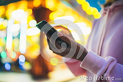 Girl pointing finger on screen smartphone on background bokeh light in night atmospheric city illumination in evening street defoc Stock Photo