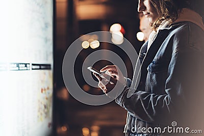 Girl pointing finger on screen smartphone on background light box in night atmospheric city map, hipster using in female hands and Stock Photo