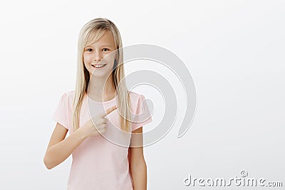 Girl pointing at her teacher who she likes. Portrait of pleased happy young child with blonde hair, pointing at upper Stock Photo