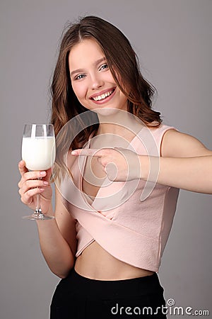 Girl points her finger at the bocal of milk. Close up. Gray background Stock Photo