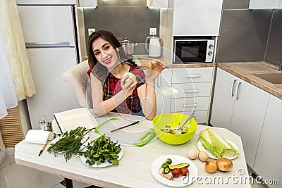 Girl posing at a kitchen table while prepares a salad of different vegetables and greens for a healthy lifestyle Stock Photo