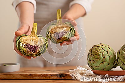 Girl prepares artichoke on a light background. Healthy eating concept. close-up Stock Photo