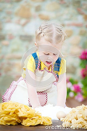 Girl preparing pasta dough on rustic wooden table in countryside Stock Photo
