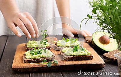 Girl preparing sandwiches with avocado spread and microgreen Stock Photo