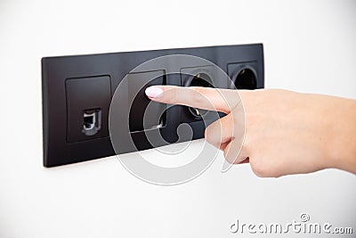 The girl presses the button of the broken electrical switch combined with the socket. Electric shock concept with faulty Stock Photo