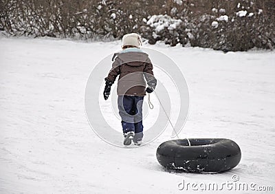 Girl pulling tube up sledding hill Stock Photo