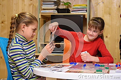A girl pulls out a card from another girl`s hand while playing a board game Stock Photo