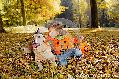 a Girl in pumpkin Haloween costume says boo for a dog Stock Photo