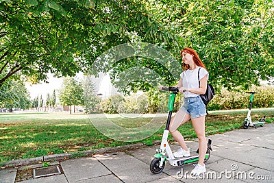 Girl pushes off ground to start riding scooter Stock Photo