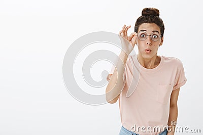 Girl putting on glasses realising how world look without blur folding lips bending towards camera amused and impressed Stock Photo