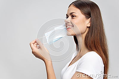 Girl putting on a medical mask smile safety white t-shirt Stock Photo